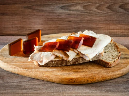 Aufgeschnittener Schweinebraten auf Brot, dazu Gelee-Scheiben als Bratensoße