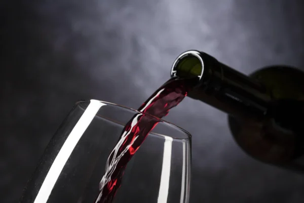 Le vin rouge sec coule de la bouteille dans le verre